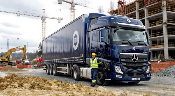 Ein Bauarbeiter lehnt an einem LKW, der auf einer Baustelle steht.