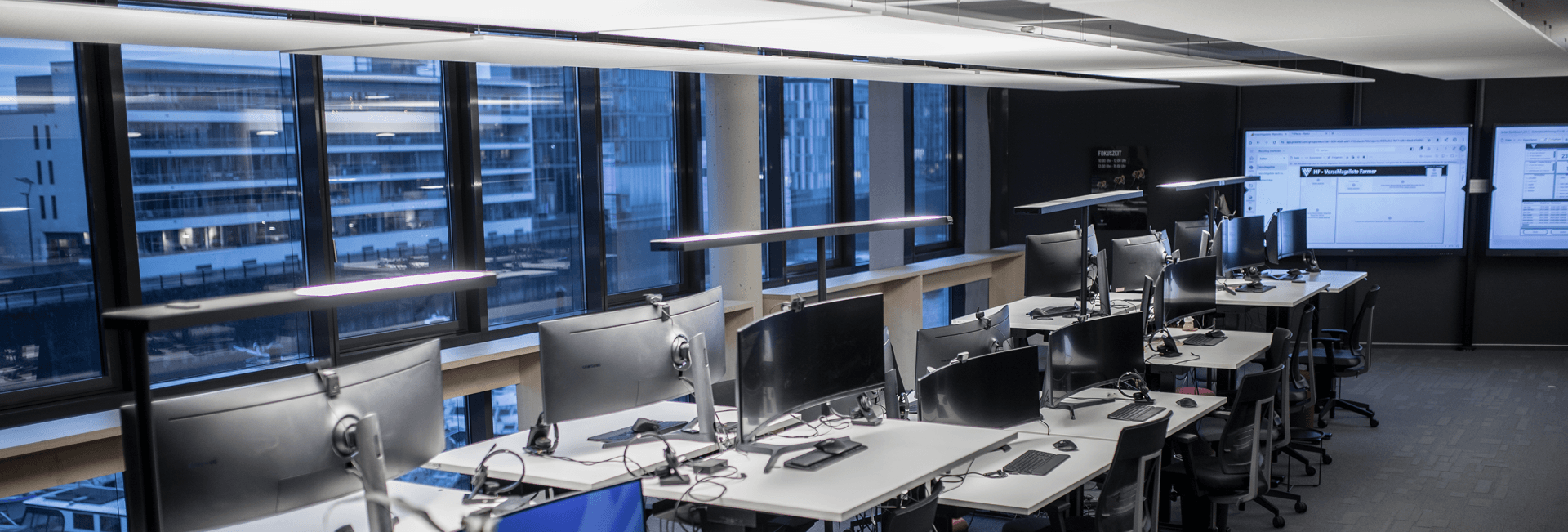 Ein modernes Büro mit leeren Schreibtischen und großen Fenstern.
