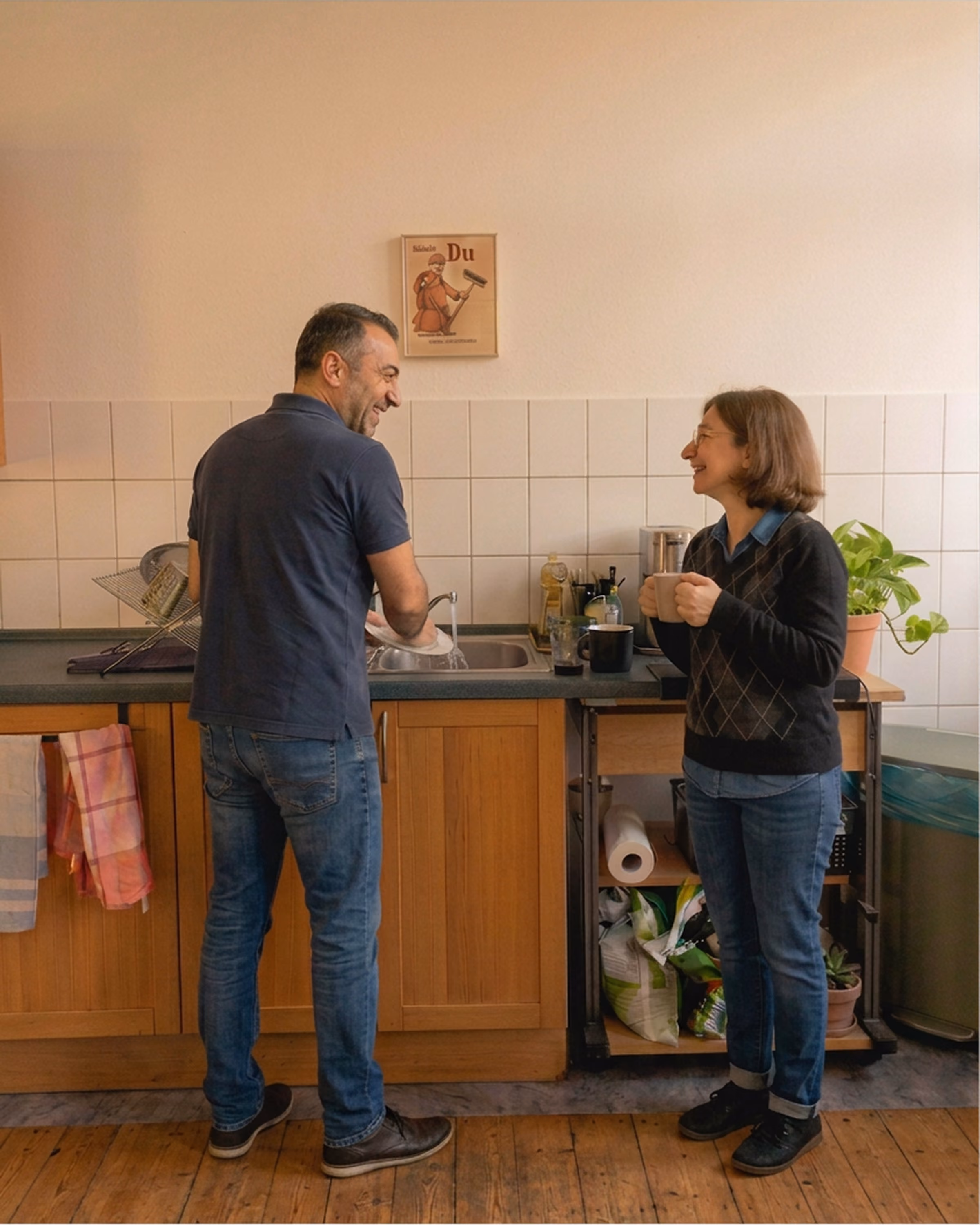 Weiße Kaffeemaschine mit geöffnetem Deckel und Filter auf Boden vor Steckdosenleiste