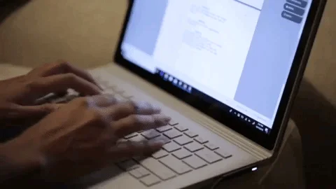 Hands typing on a white laptop keyboard with a document open on the screen.