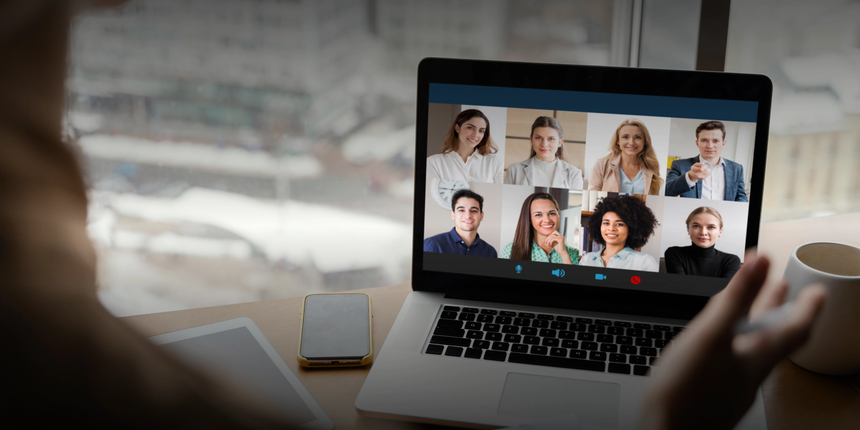 Person participating in a video conference with eight colleagues displayed on a laptop screen.
