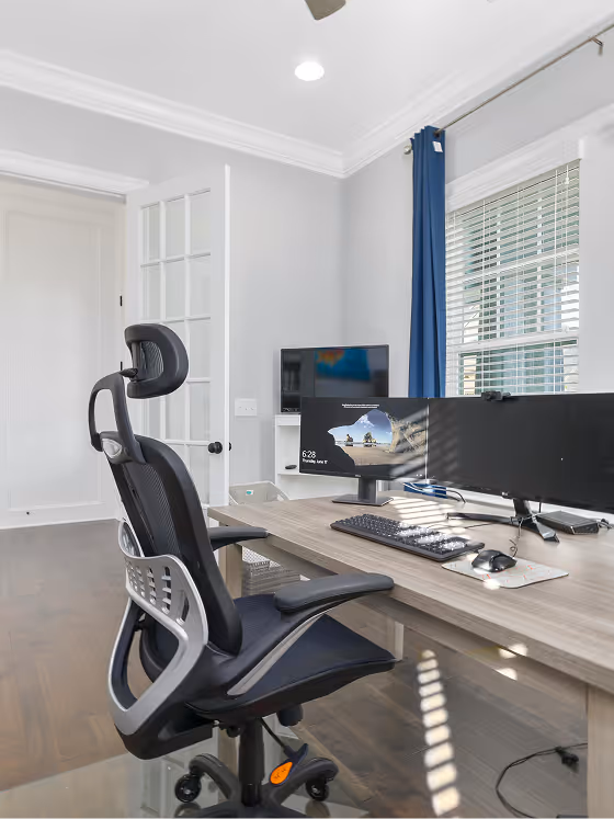 Photographie d'un bureau composé de plusieurs écrans ainsi que d'une chaise ergonomique.