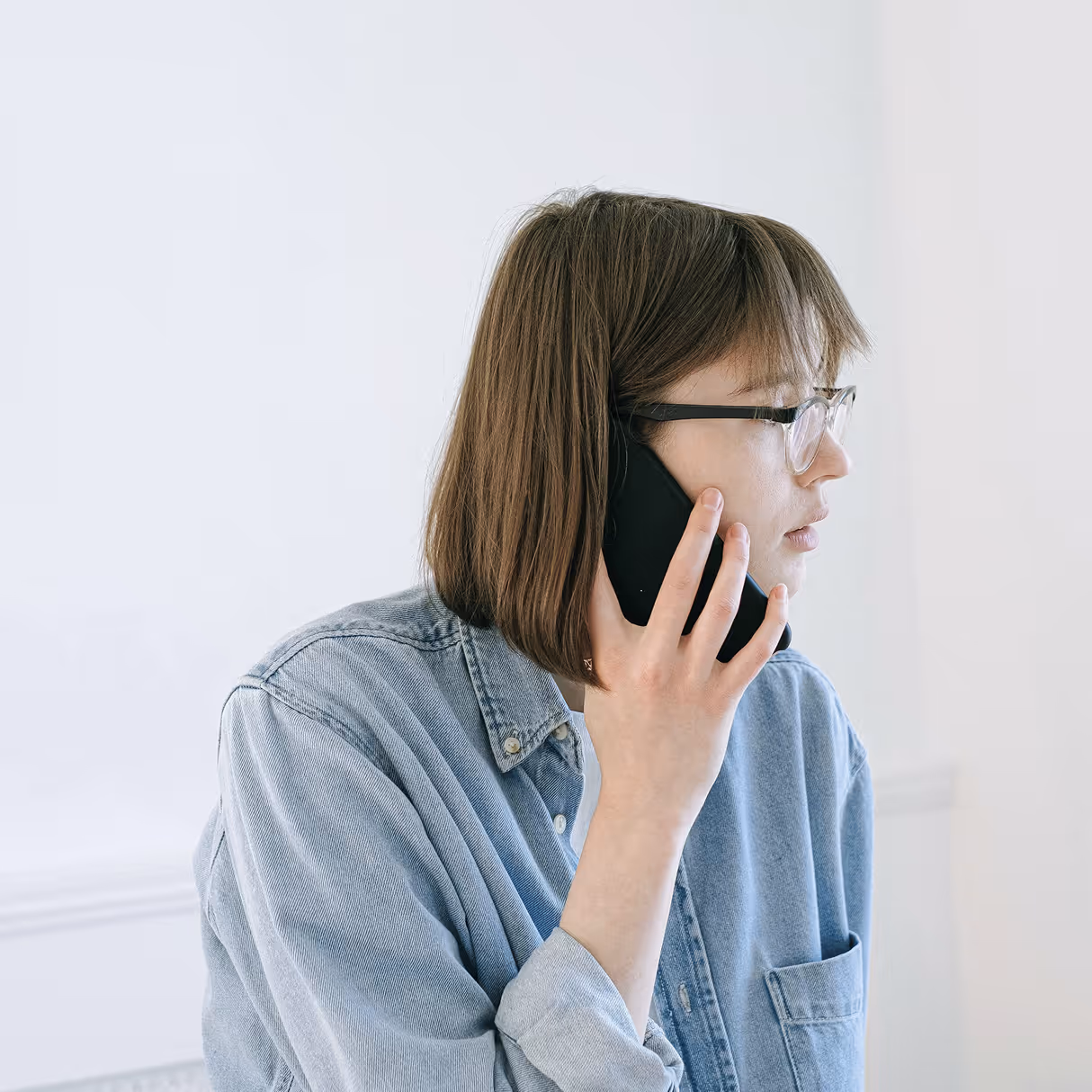 Photographie d'une jeune femme de profil passant un appel téléphonique depuis son smartphone.