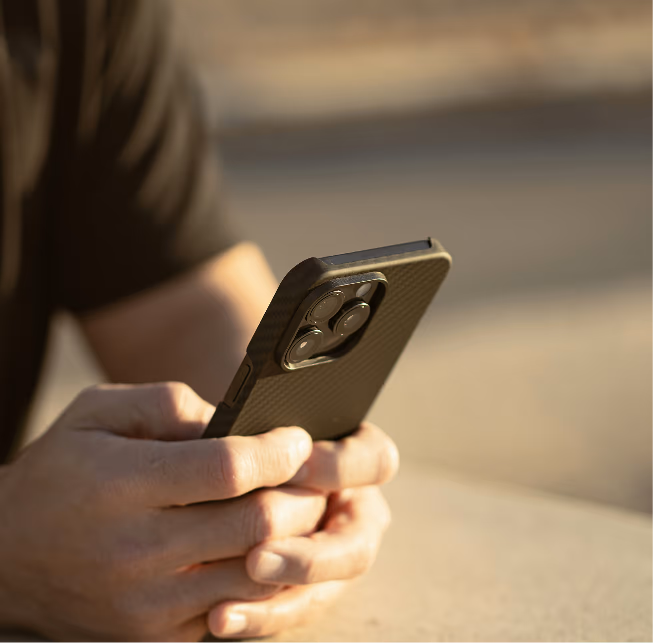 Photographie d'une personne tenant son smartphone entre ses mains, vue rapprochée de ses mains.