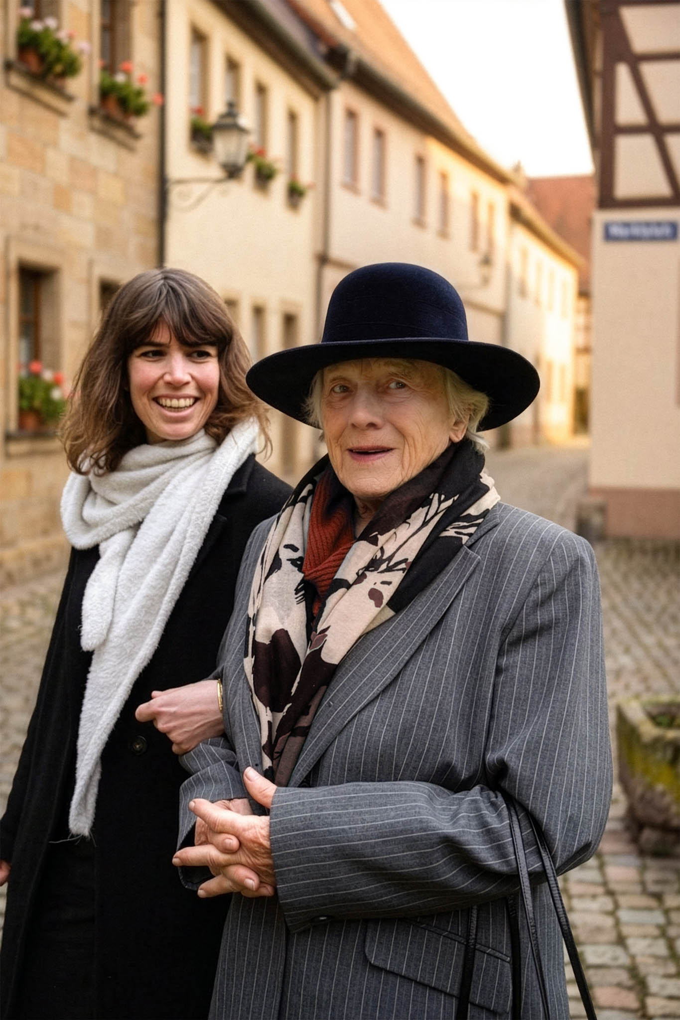 Zwei Frauen unterschiedlicher Generationen sitzen draußen und unterhalten sich lächelnd auf Stühlen.