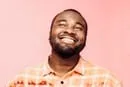 A man with a beard smiling and wearing a plaid shirt.