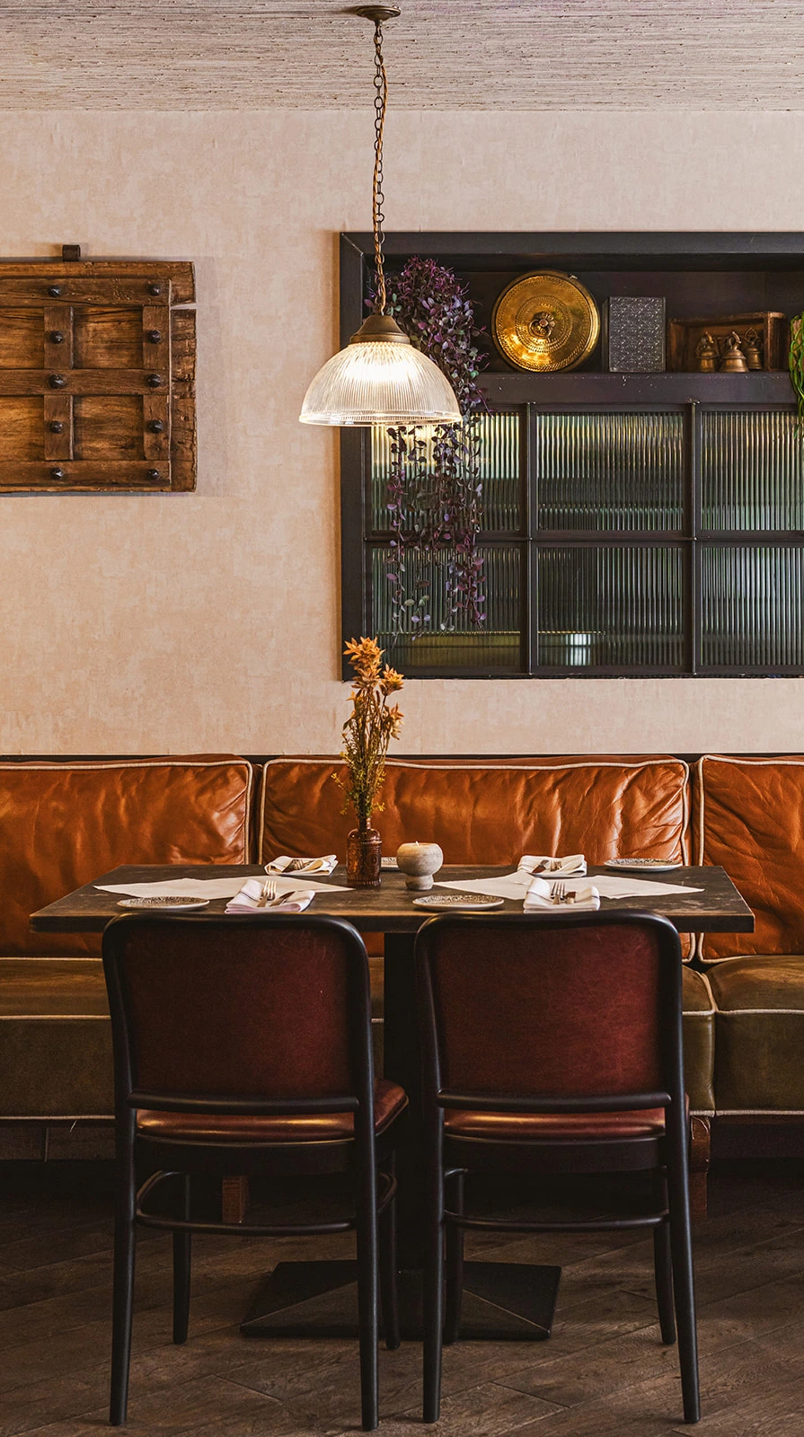 Leather booth dining table at Dabbawal Indian restaurant in Newcastle, lit by a vintage pendant lamp