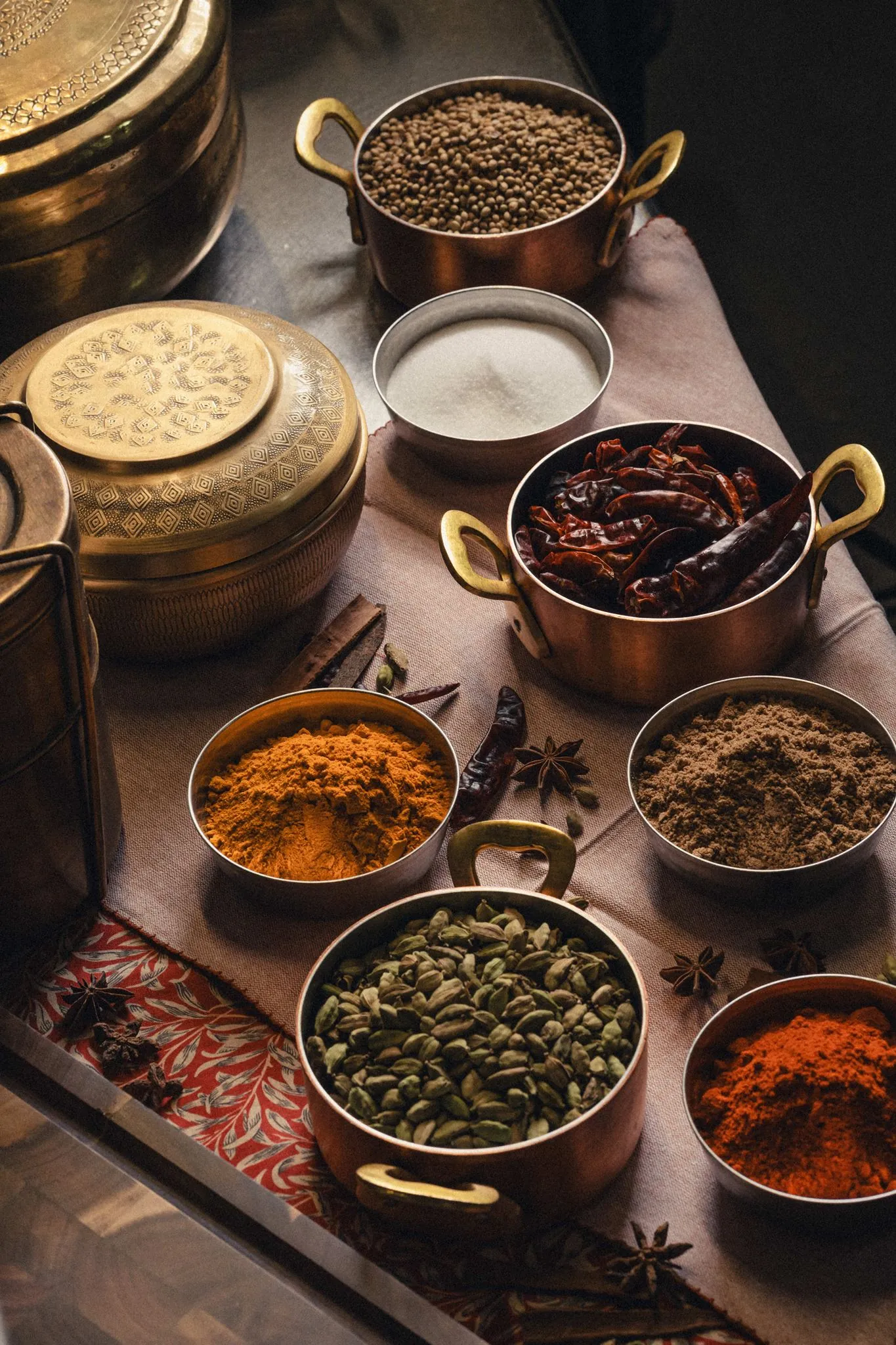 Whole Indian spices in copper pans, including cardamom, cumin and dried chillies, at Dabbawal Newcastle
