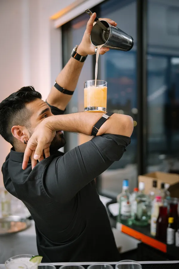 A mixologist pouring a drink at an event catered by Bartleby & Sage. 