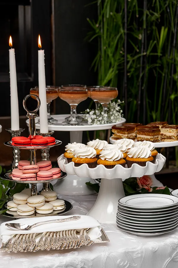 Dessert tower by Bartleby & Sage, with pink and white macarons, cupcakes, and chocolate mousse cups lit by taper candles