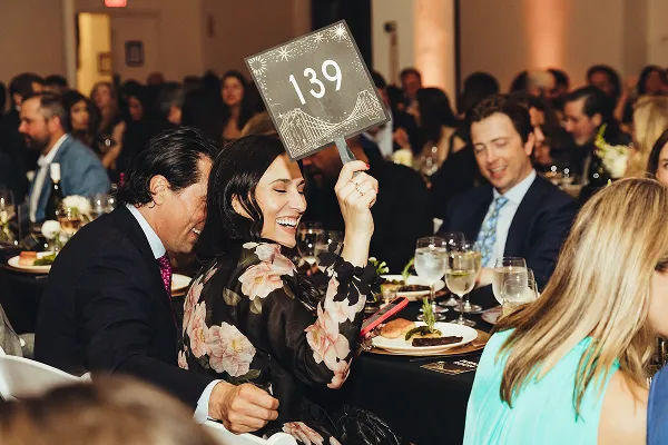 A gala guest raising a paddle at an event catered by Bartleby & Sage