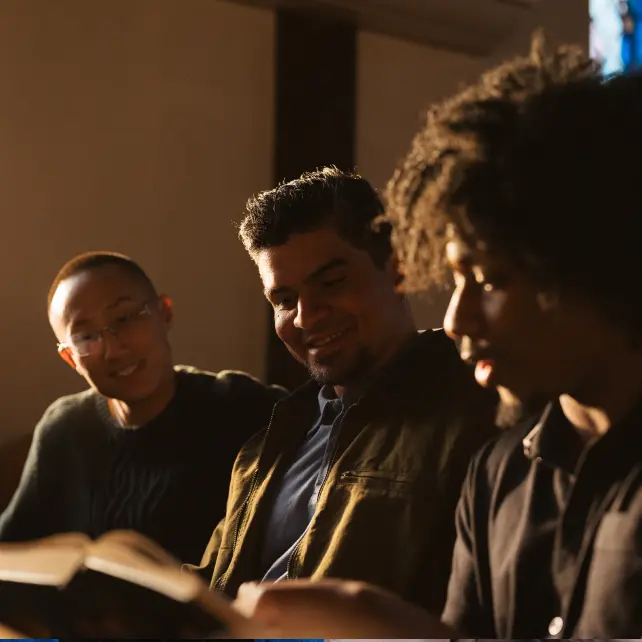 3 young men looking at and discussing the Bible