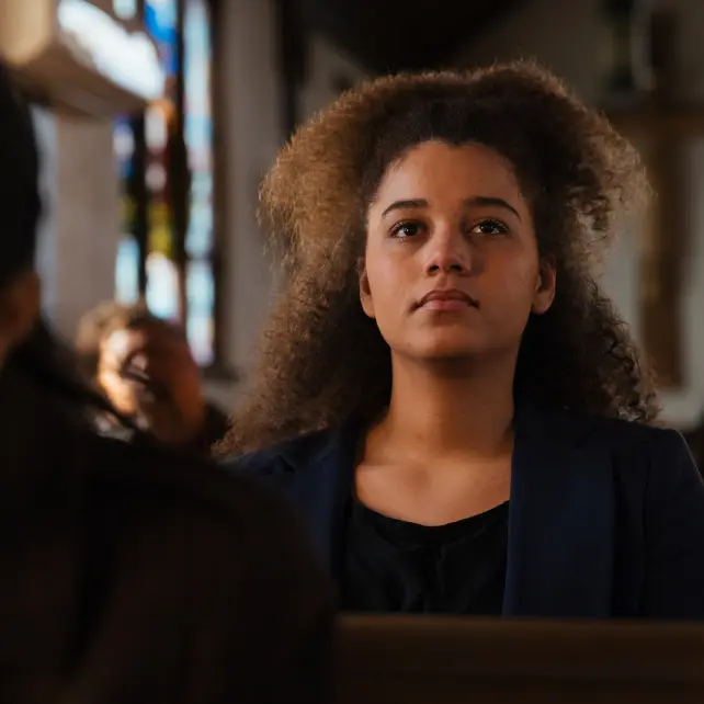 Young lady in blue and black listening in church service