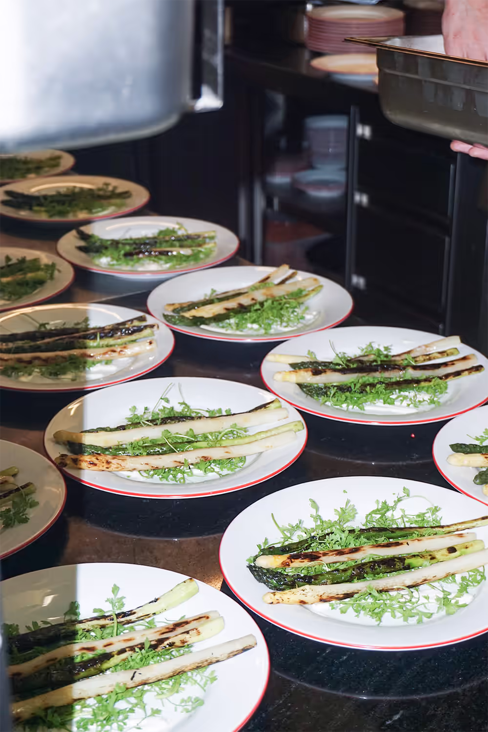 Reihe angerichteter Teller mit gegrilltem Spargel und Kräutersalat auf dem Pass