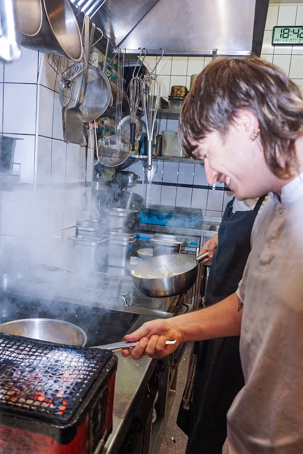Köchin arbeitet am Grill in der Küche, Dampf steigt auf