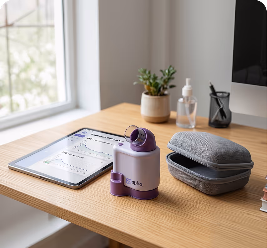 A go spiro respiratory device on a wooden desk next to a tablet displaying respiratory wellness data and an open gray carrying case.