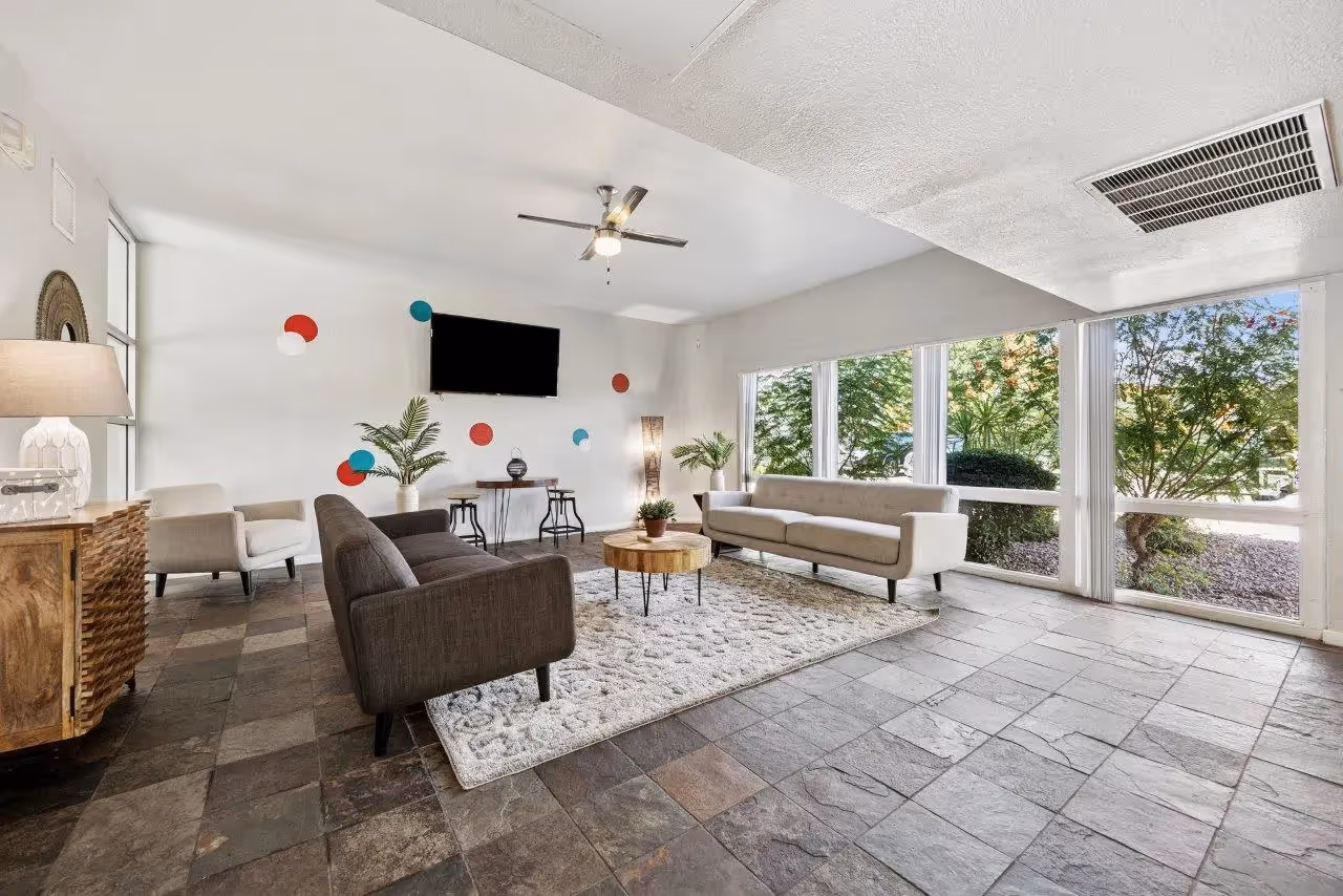 Leasing office with seating area featuring sofa, coffee table, and wall art with logo