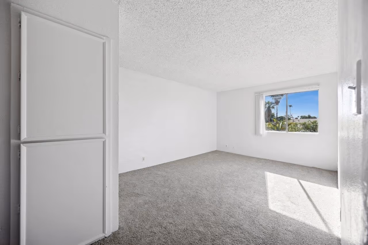 Unfurnished bedroom with large window and carpet