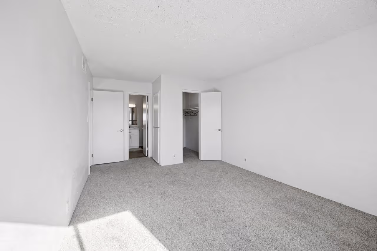 Unfurnished bedroom with carpet featuring bathroom and walk-in closet