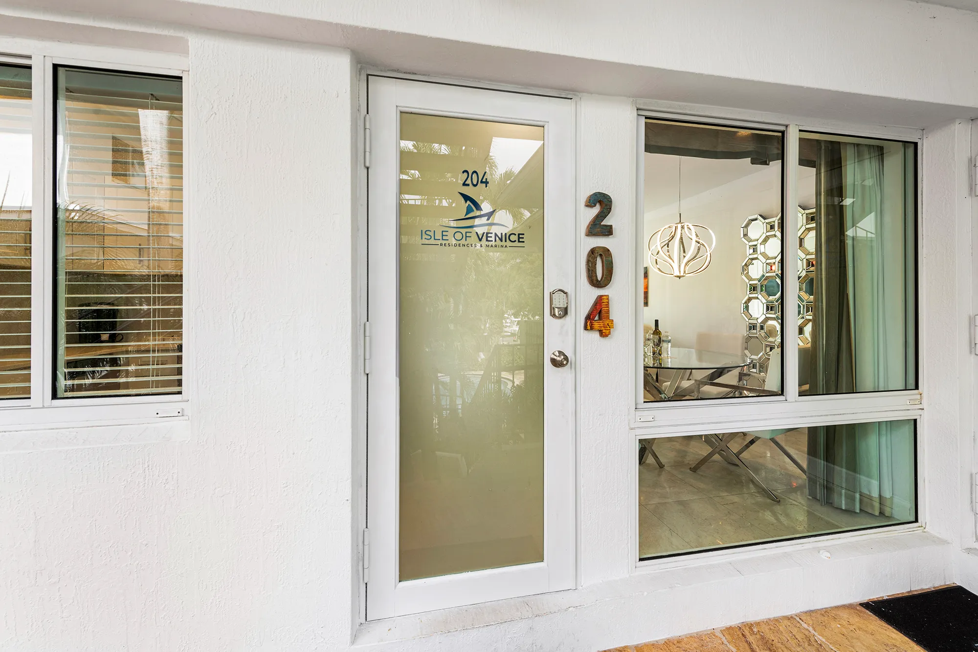 Entrance door of unit 204 at Isle of Venice Residences & Marina with windows showing modern interior dining area.