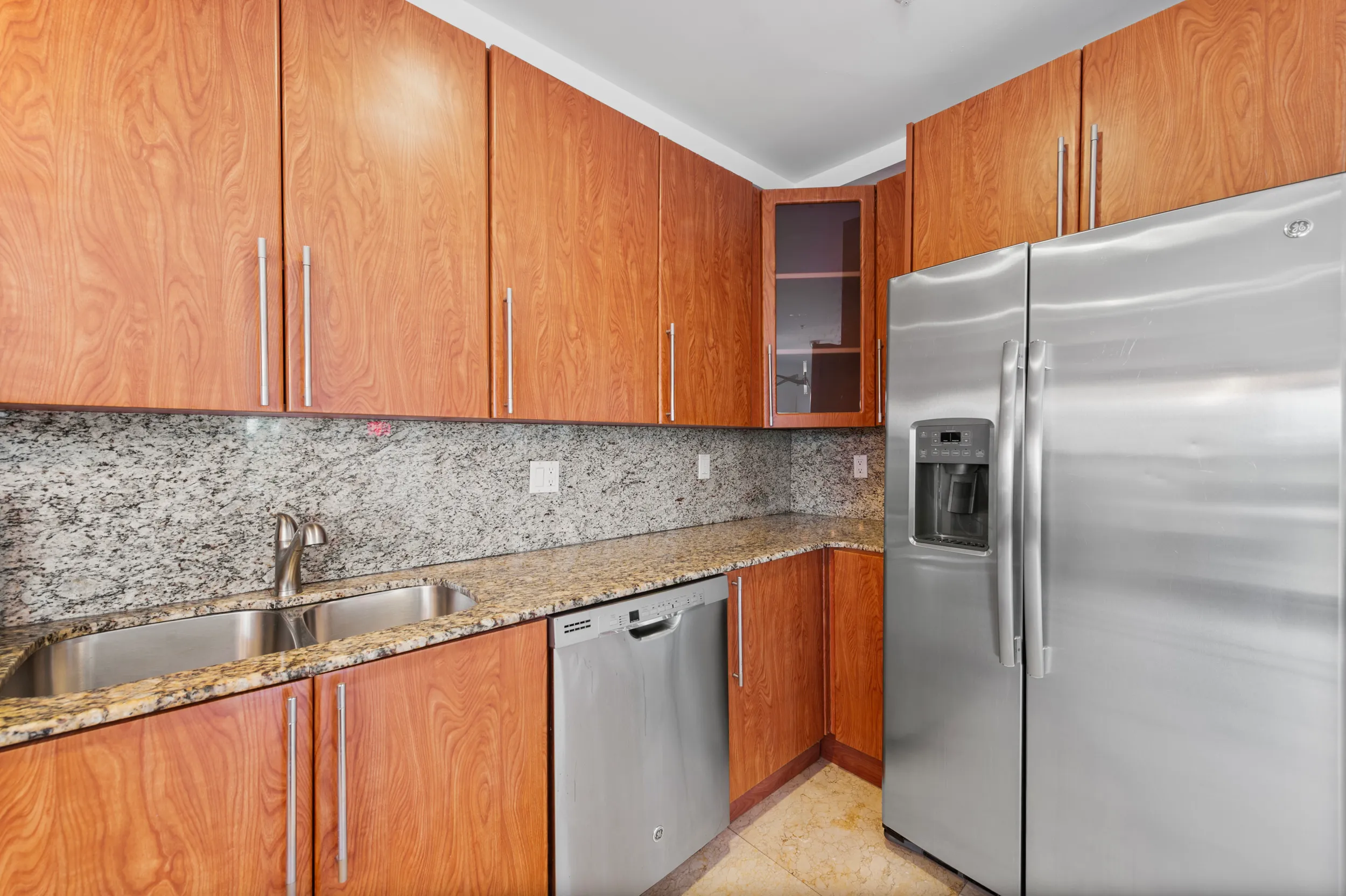 Modern kitchen with wooden cabinets, granite countertops, stainless steel sink, dishwasher, and a large stainless steel refrigerator with water dispenser.