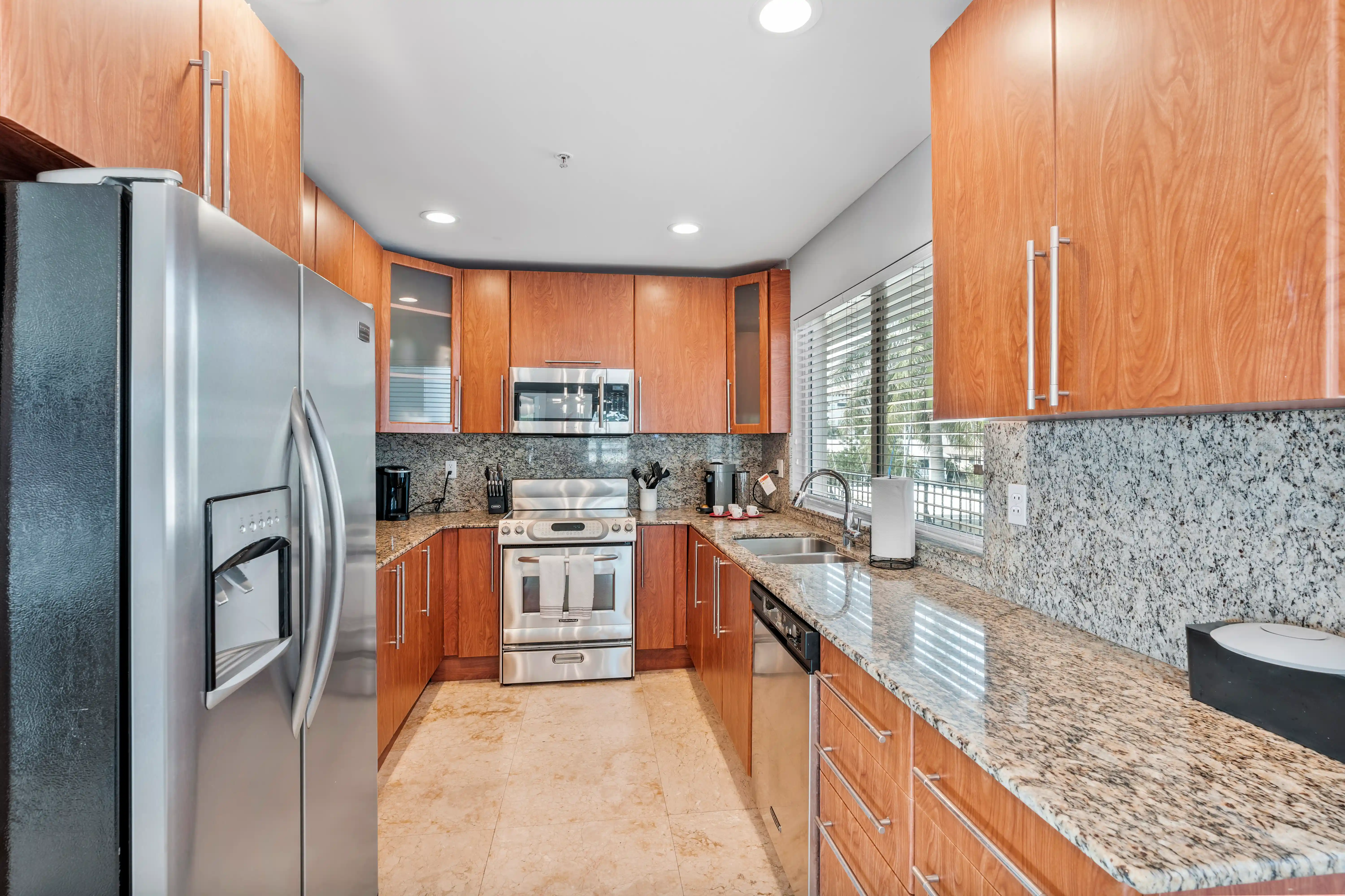 Modern kitchen with wooden cabinets, granite countertops, stainless steel refrigerator, oven, microwave, and dishwasher.