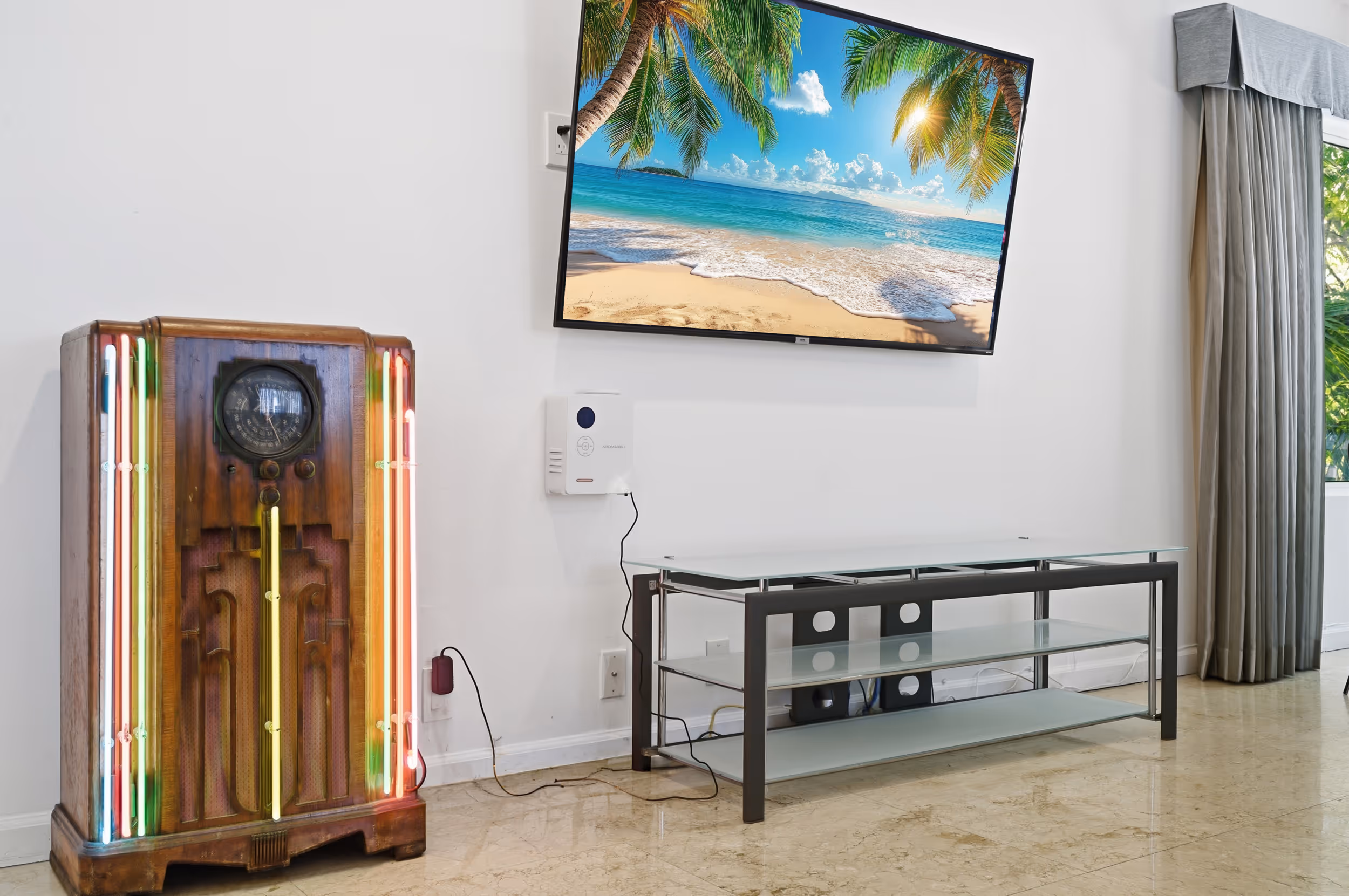 Living room with vintage wooden radio, modern glass TV stand, and wall-mounted TV showing a beach scene.