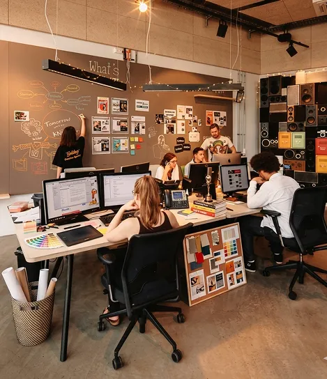 A group of people sitting at a table working on computers.