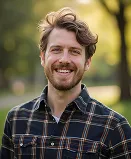 A man in a plaid shirt smiles at the camera.