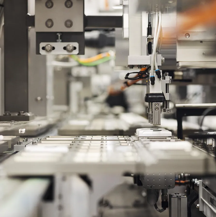 Close-up of a robotic arm assembling or inspecting objects on an automated conveyor belt in a factory.