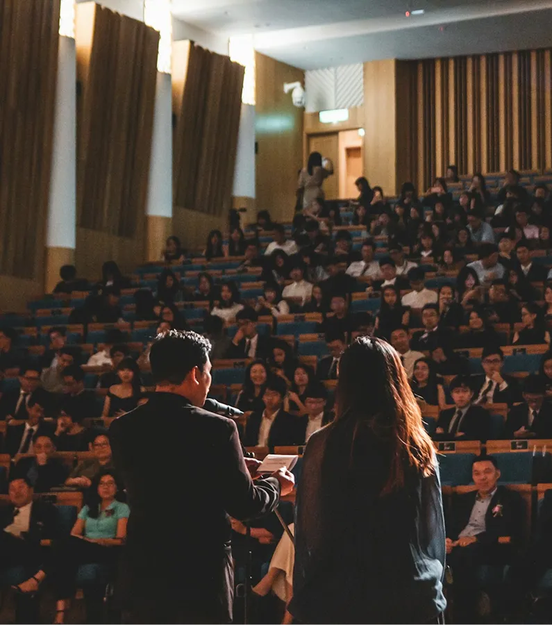 A man standing next to a woman in front of a crowd of people.