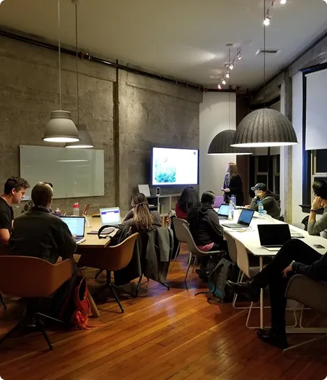 A group of people sitting around a table with laptops.