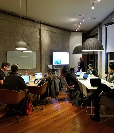 A group of people sitting around a table with laptops.