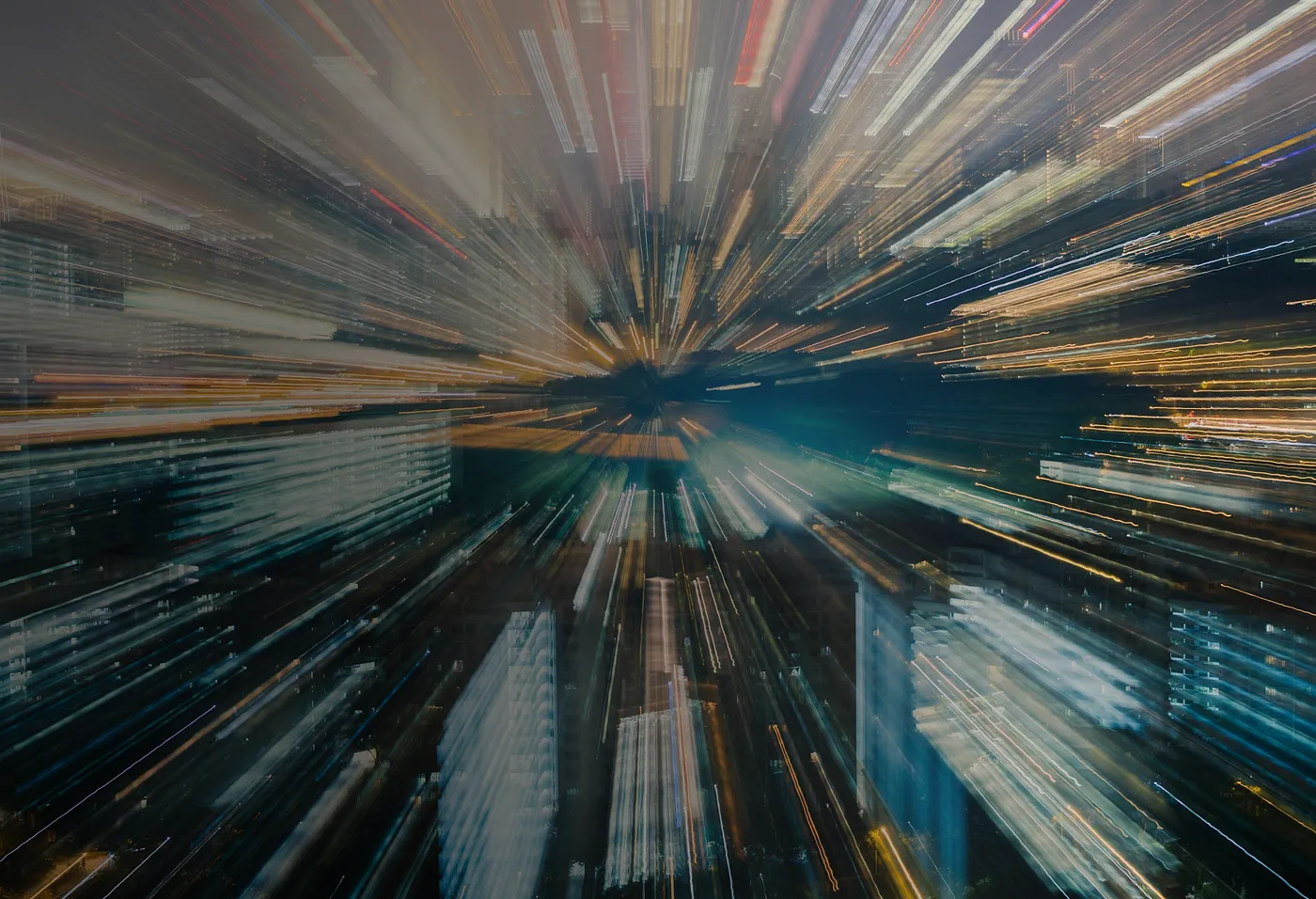 Cityscape at night with light trails creating a radial blur effect from the center.