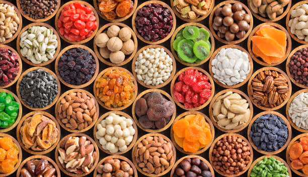 Multiple wooden bowls filled with assorted dried fruits, nuts, seeds, and colorful snacks.
