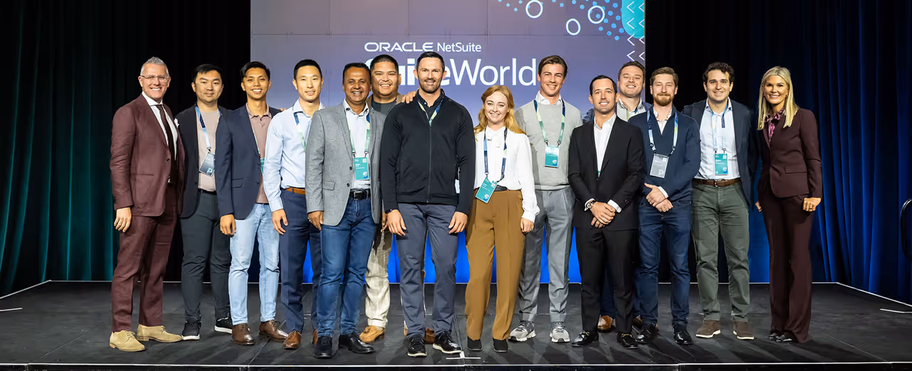 Group of thirteen people standing on stage at Oracle NetSuite SuiteWorld event.
