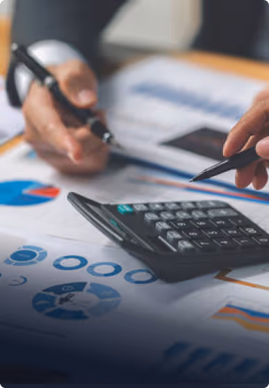 Two hands with pens pointing at financial charts and a calculator on a desk.