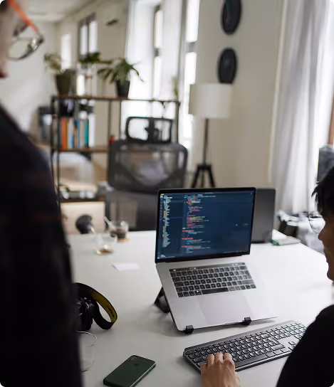 Person coding on a laptop at desk with wireless keyboard in a modern office space.