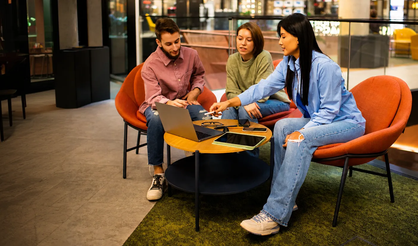 A group of people sitting around a table with laptops.