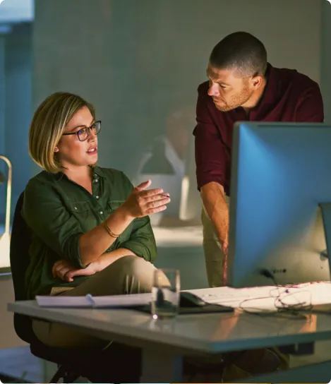 A man and a woman sitting in front of a computer.