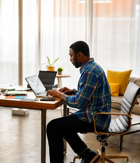A man sitting at a desk using a laptop computer.