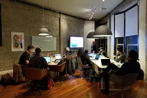 A group of people sitting around a table working on laptops.