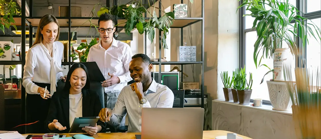 A group of people standing around a laptop computer.