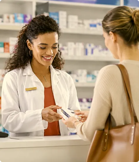 A woman in a pharmacy holding a credit card.