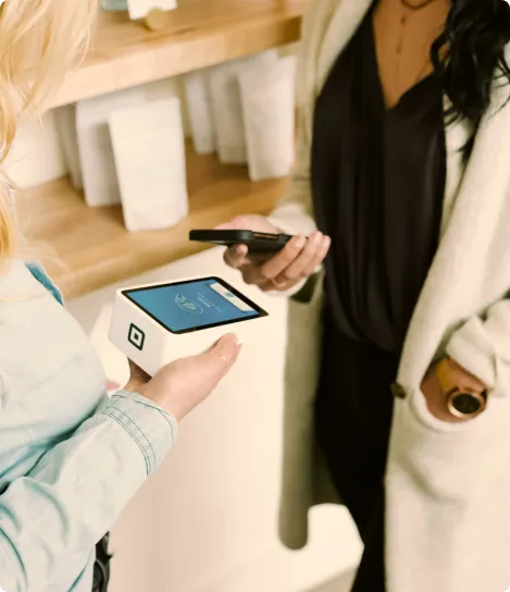 Two women standing next to each other holding cell phones.