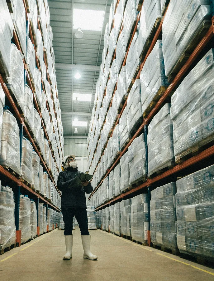 A woman standing in a warehouse surrounded by stacks of boxes.