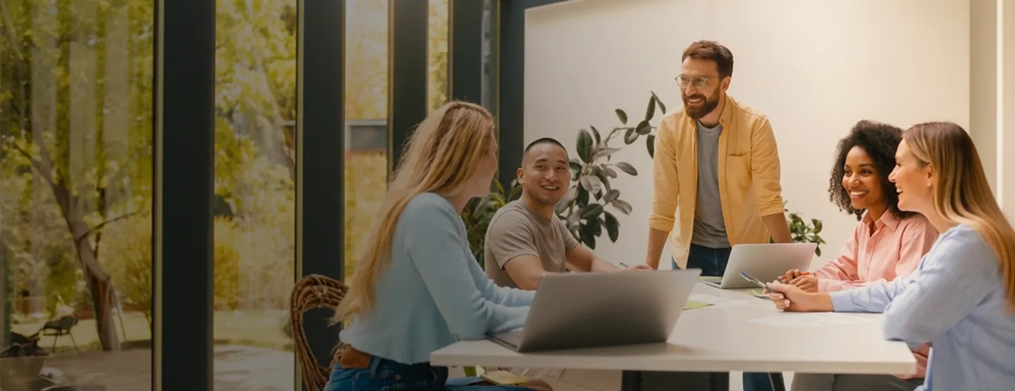 A group of people sitting around a table with laptops.