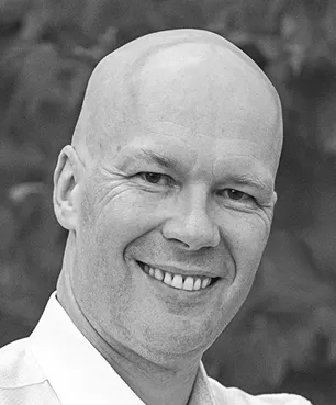 A black and white photo of a smiling man.