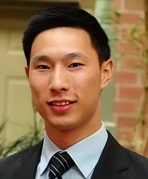 A man in a suit and tie standing in front of a building.