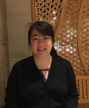 A woman standing in front of a wooden wall.